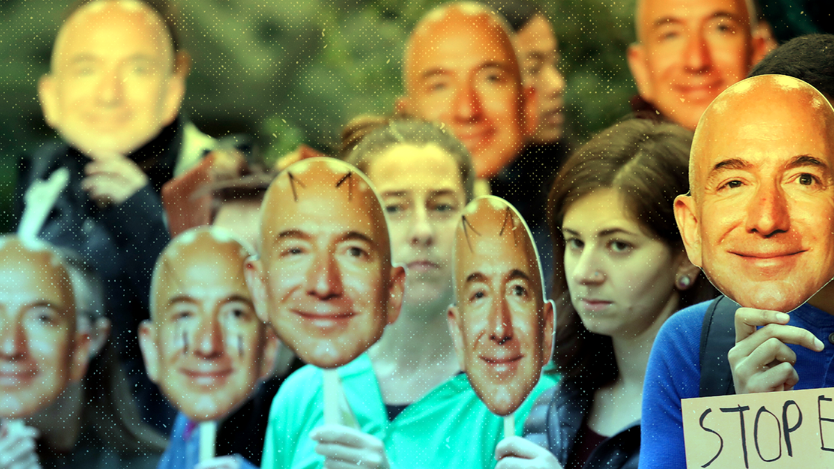 Demonstrators hold images of Amazon CEO Jeff Bezos near their faces during a Halloween-themed protest at Amazon headquarters.