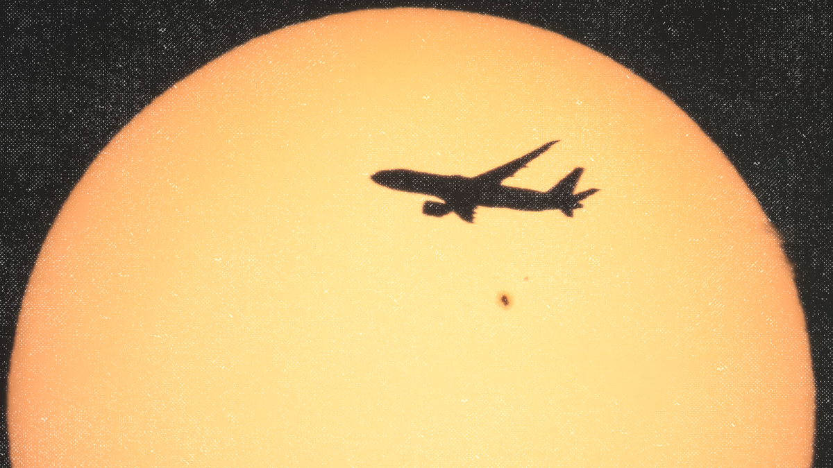 A Boeing 777 in mid-air is silhouetted against the Sun with a Sun spot.