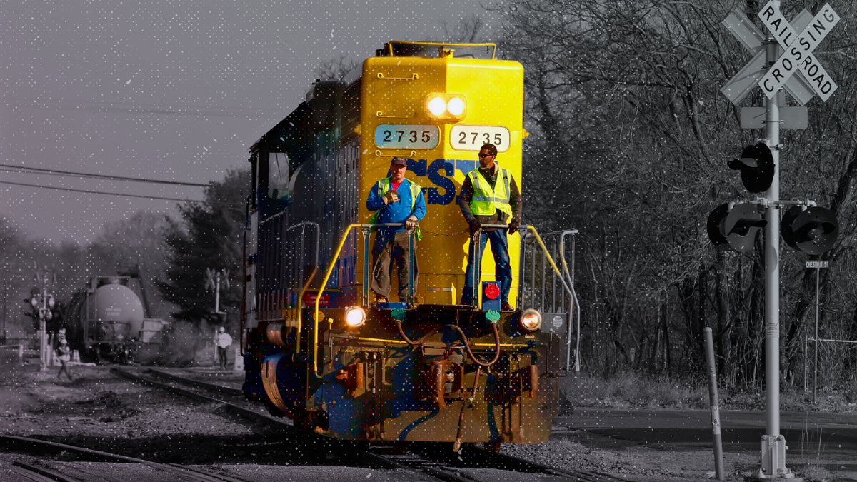 Crew members ride on a locomotive after leaving empty tank cars near derailed train cars in Paulsboro, N.J.